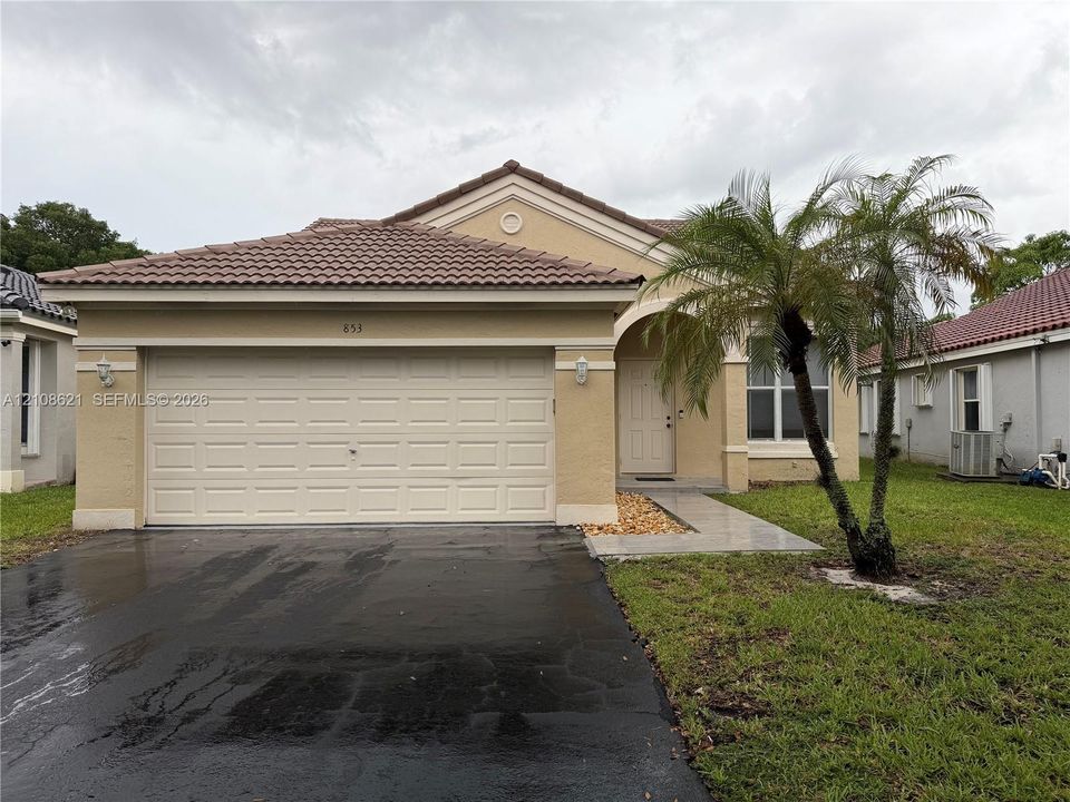 Stucco exterior featuring a tiled roof, arched entryway, and two-car garage