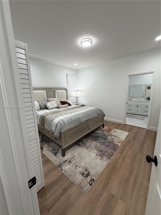 Neutral-toned interior featuring wood-finish flooring, louvered closet doors, and recessed lighting