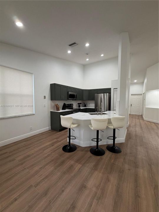 Kitchen featuring dark-toned cabinetry, light-toned countertops, wood-finish flooring, and recessed ceiling lighting