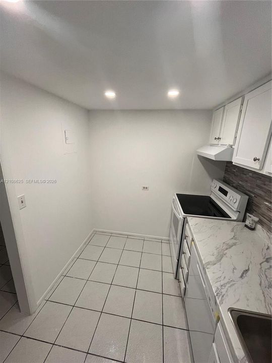 Kitchen featuring white cabinetry, stone-patterned countertops, recessed lighting, tile flooring, and a decorative backsplash