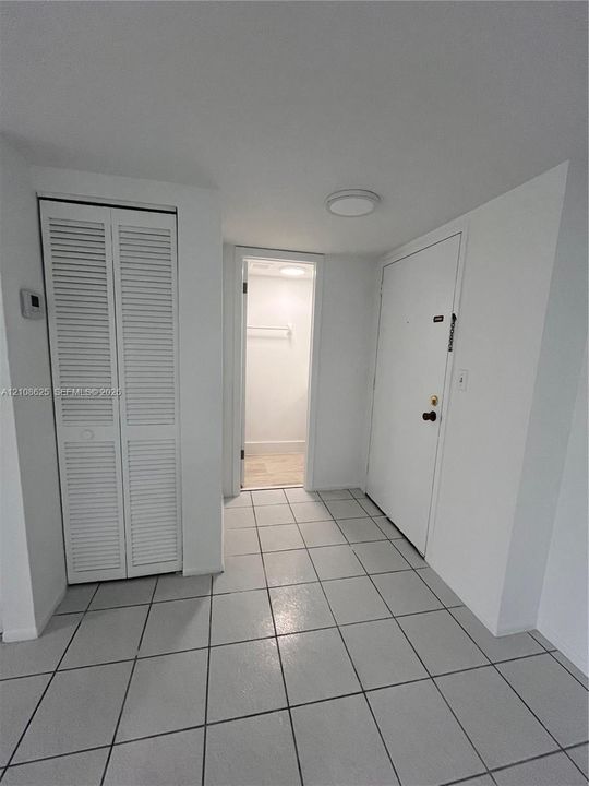 Foyer featuring neutral tile flooring, louvered bi-fold closet doors, and a flush-mount ceiling light