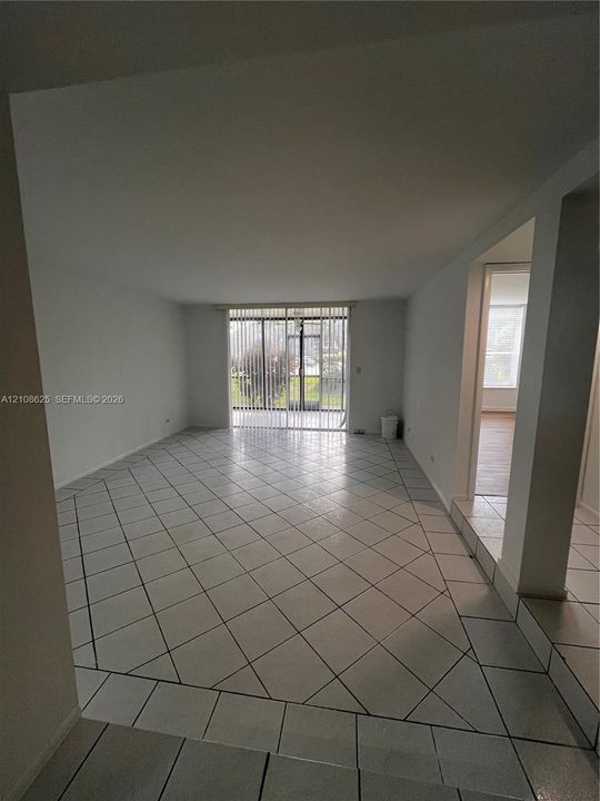 Open-concept interior featuring diagonal tile flooring and sliding glass doors with vertical blinds