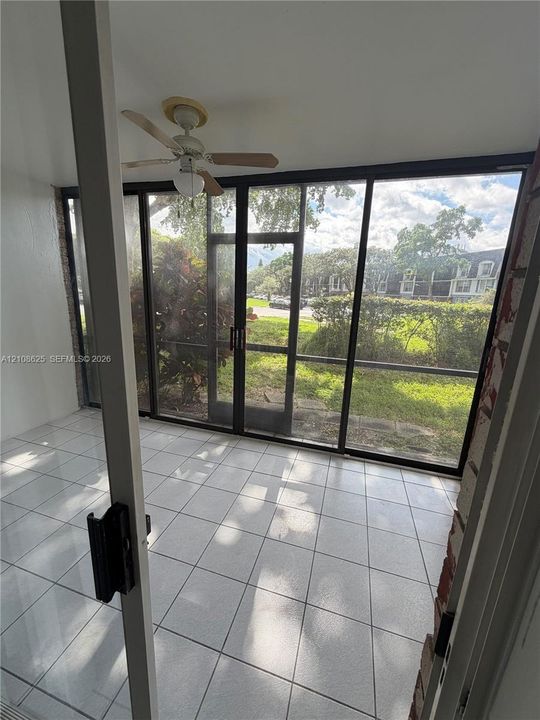 Enclosed patio featuring white tile flooring, ceiling fan with integrated lighting, and expansive screened panels