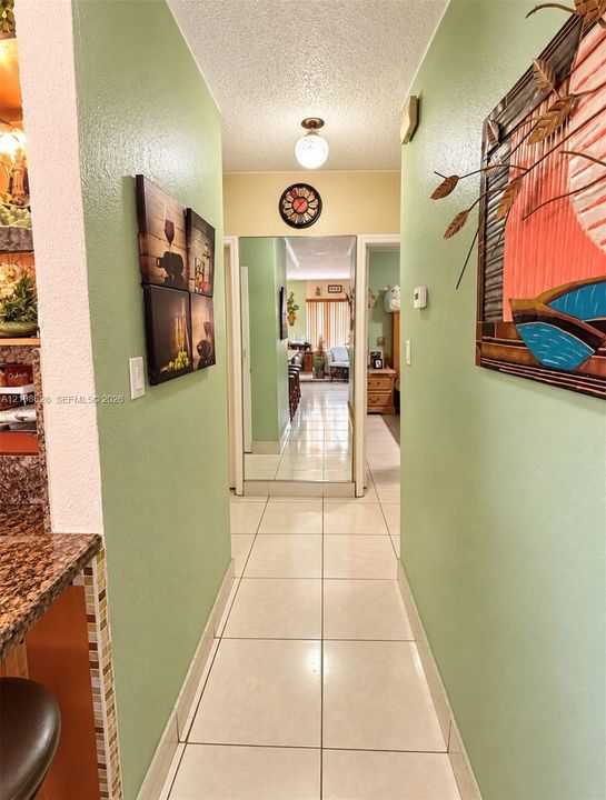 Interior hall featuring large-format ceramic tile flooring, full-length mirror paneling, and flush-mount overhead lighting