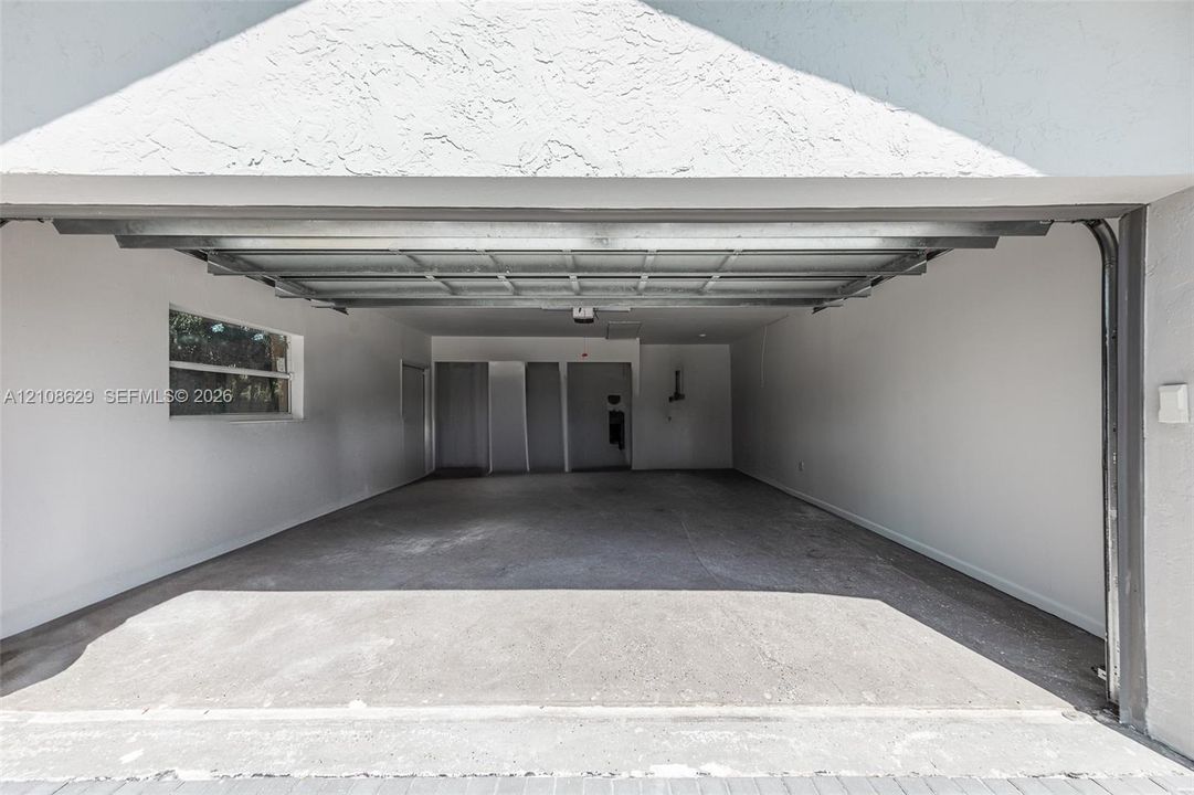 Two-car garage featuring a concrete floor, motorized overhead door, and a side-wall window