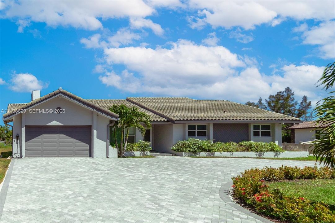 Single-story residence featuring a tile roof, light-toned exterior finish, paver driveway, and integrated garage