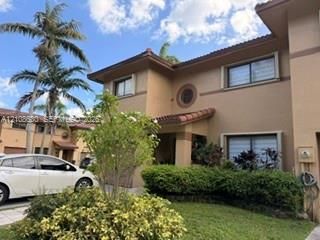 Two-story exterior featuring stucco siding, a circular accent window, clay tile roofing, and a recessed entryway