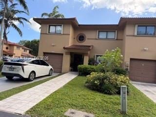 Two-story exterior featuring a stucco facade, dual attached garages, a decorative circular window, and a tiled walkway