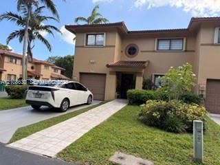 Two-story exterior featuring a stucco facade, tile roof, integrated garage, decorative circular window, and a paved walkway