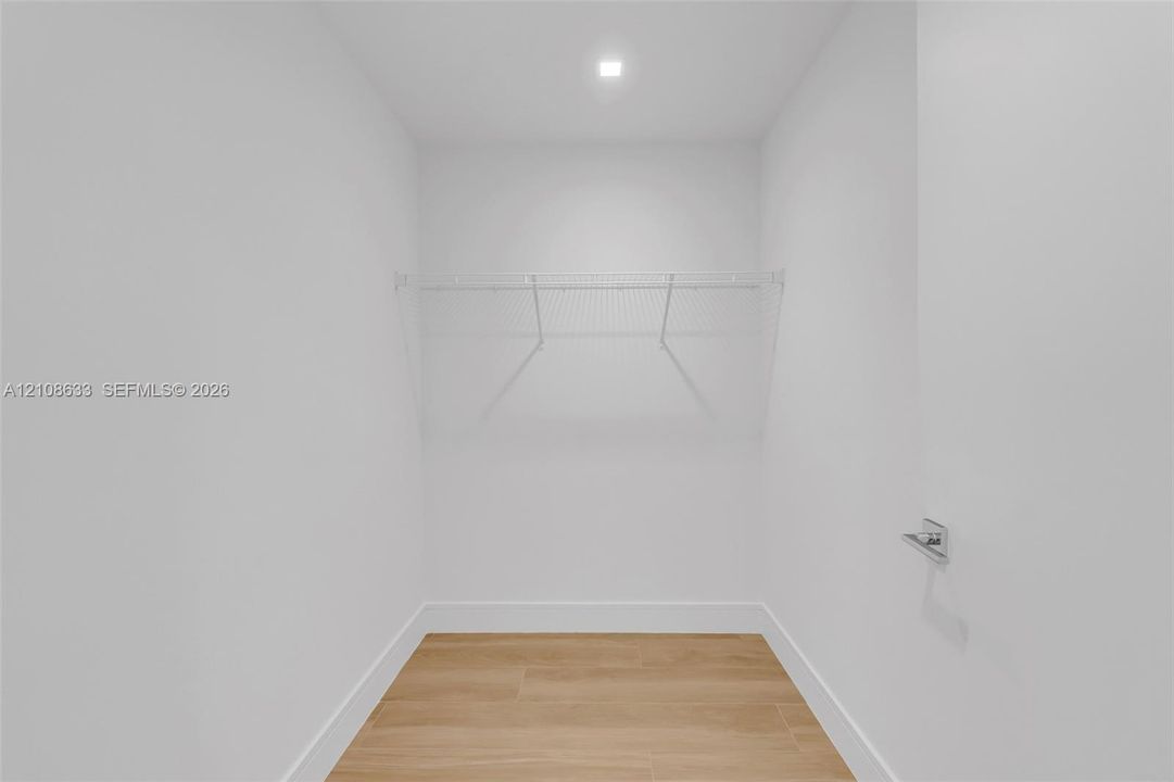 Storage space featuring wood-finish flooring, white walls, recessed ceiling lighting, and built-in wire shelving