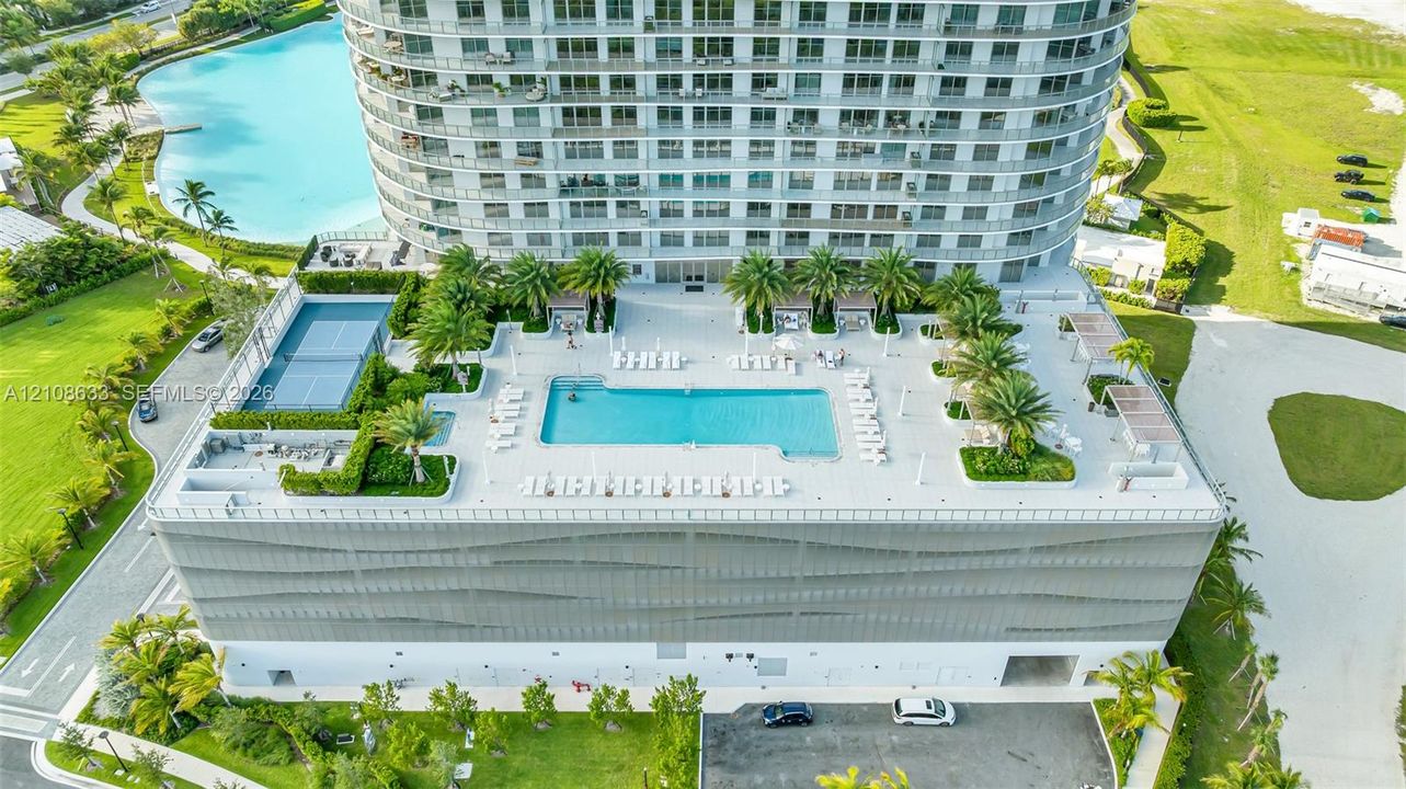Elevated deck featuring a swimming pool, tennis court, landscaped planters with palm trees, and structural screening