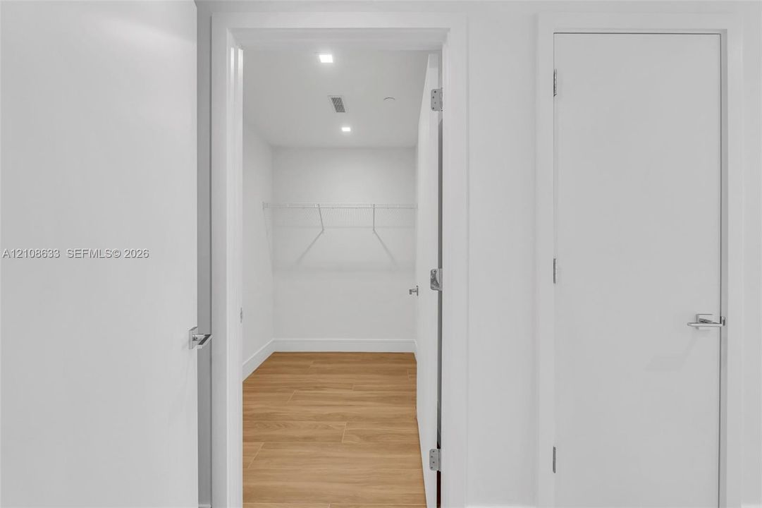 Storage space featuring wood-finish flooring, white walls, recessed ceiling lighting, and wire shelving