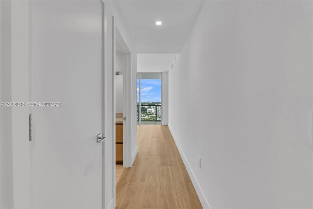 Hallway featuring wood-finish flooring, recessed lighting, and access to a balcony with an expansive exterior outlook
