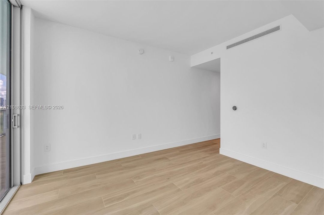 Neutral interior space featuring wood-finish tile flooring, floor-to-ceiling glass sliding door, and recessed ceiling HVAC system