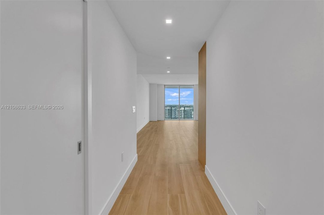Hallway featuring wood-finish flooring, recessed lighting, and floor-to-ceiling glass sliding doors