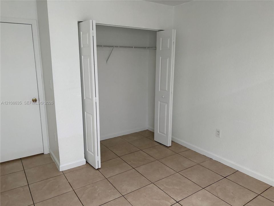 Neutral-toned floor tiling, bi-fold closet doors, and solid-core interior doors