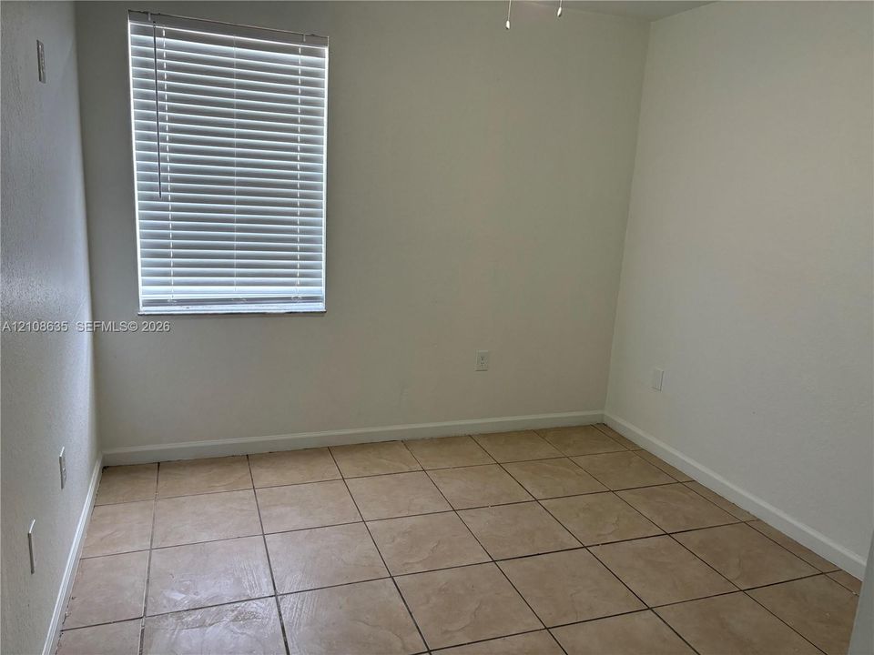 Room featuring large-format ceramic tile flooring, neutral walls, and a horizontal blind window covering