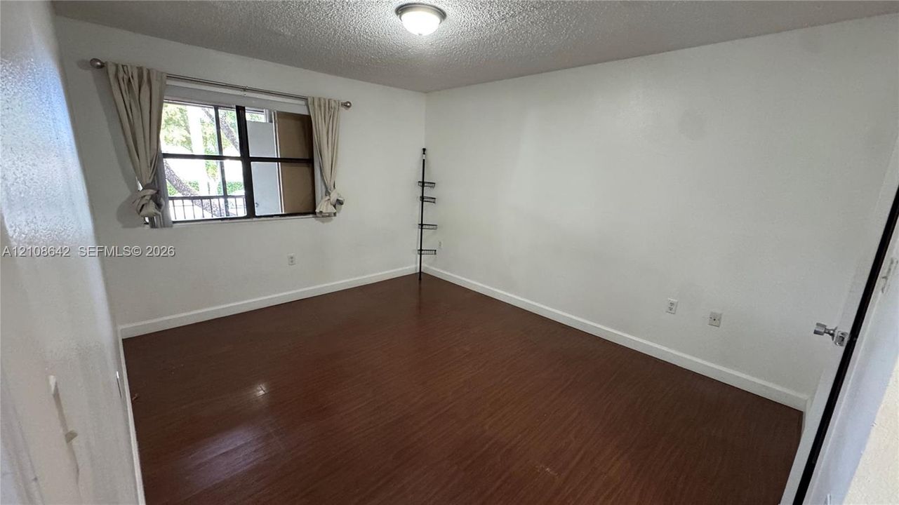 Interior room featuring wood-finish flooring, a multi-pane window, and a ceiling-mounted light fixture