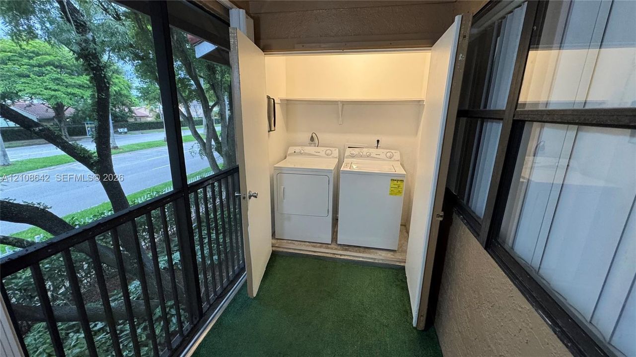 Screened patio enclosure featuring a built-in laundry closet with shelving and sliding glass windows