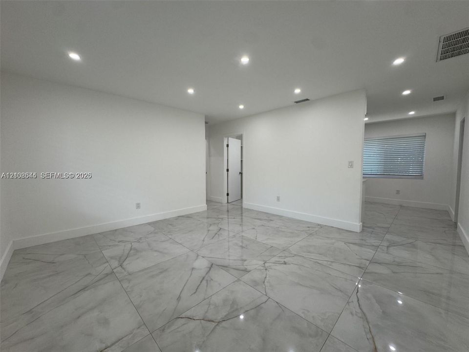 Open-concept interior featuring large-format polished stone-finish floor tiles and recessed ceiling lighting