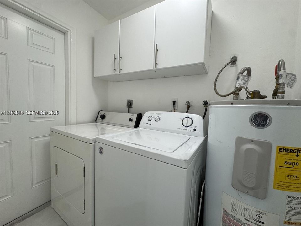 Utility area featuring white flat-panel upper cabinetry, a six-panel door, and dedicated washer and dryer hookups