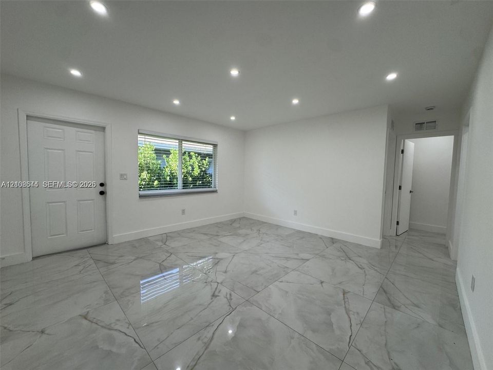 Large-format tile flooring, recessed ceiling lighting, and six-panel interior door