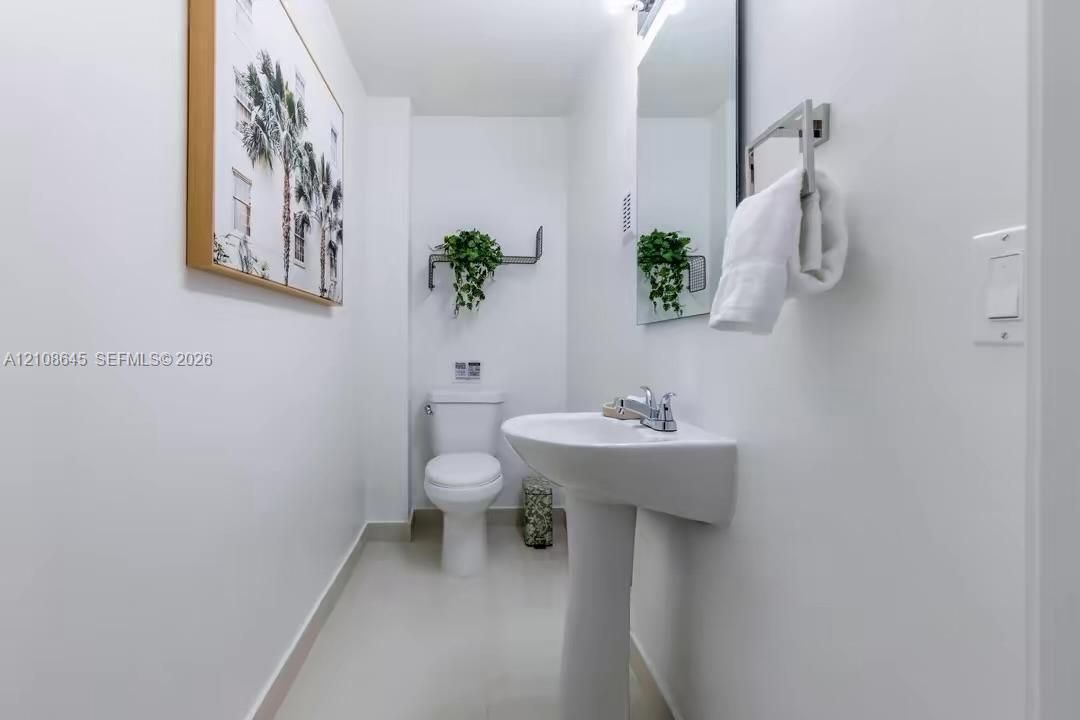 Half bath on 1st floor. Pedestal sink with a chrome single-handle faucet, rectangular wall-mounted mirror, and tile flooring