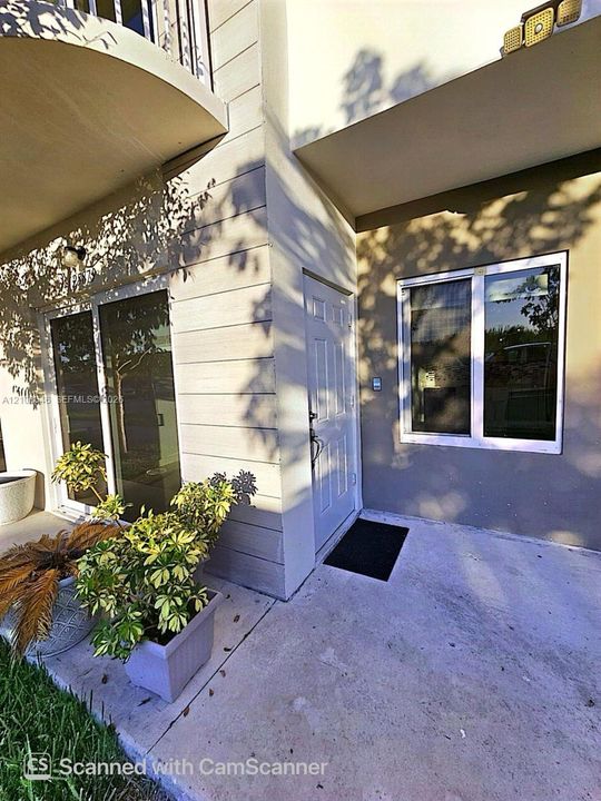 Exterior entrance featuring a concrete patio, sliding glass door, single-panel entry door, and multi-pane window