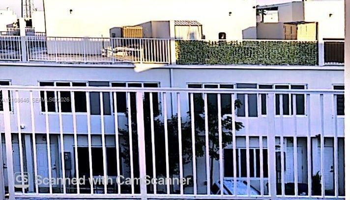 Exterior facade featuring white siding, a rooftop deck with metal railing, and multiple sliding glass windows