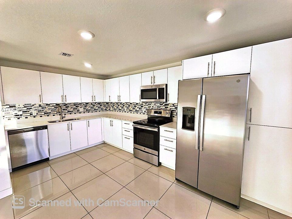 Kitchen featuring white cabinetry, stainless steel appliances, a mosaic tile backsplash, tile flooring, and recessed lighting