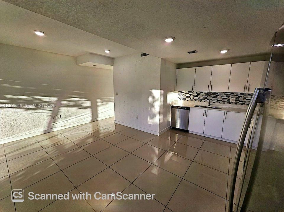 Kitchen featuring white cabinetry, mosaic tile backsplash, stainless steel dishwasher, and tile flooring with recessed lighting