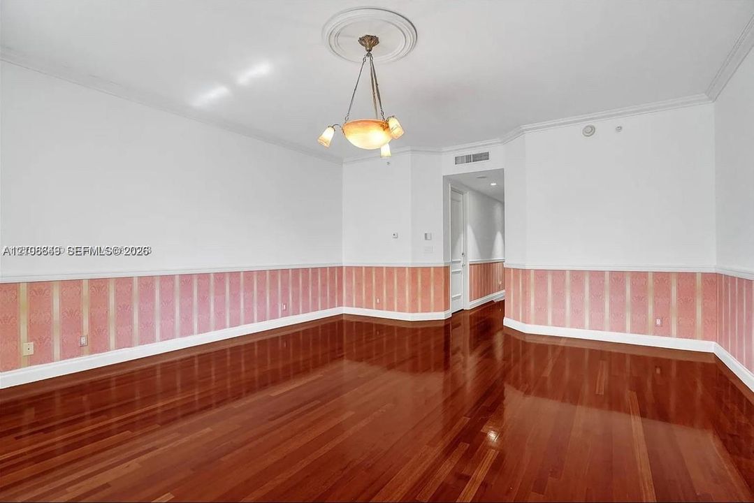 Interior space featuring high-gloss wood-finish flooring, decorative wall wainscoting, and a central ceiling medallion with a multi-arm light fixture