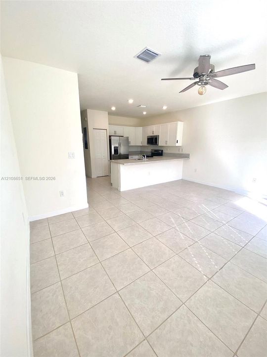 Kitchen featuring white cabinetry, solid-surface countertops, stainless steel appliances, tile flooring, and recessed ceiling lighting