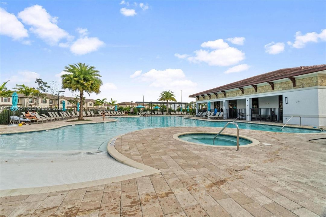 Community swimming pool featuring a zero-entry basin, integrated spa, and extensive paver decking
