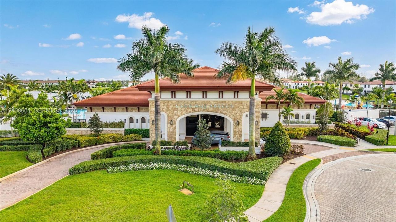 Mediterranean-style exterior featuring stone veneer siding, a tile roof, a covered porte-cochère, and professionally manicured landscaping