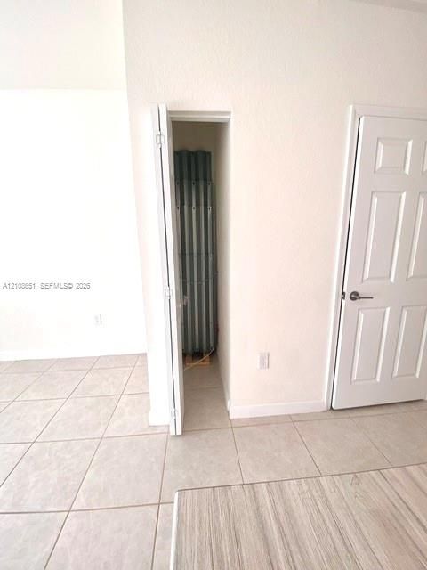 Neutral ceramic floor tiling, six-panel interior door, and built-in closet storage space