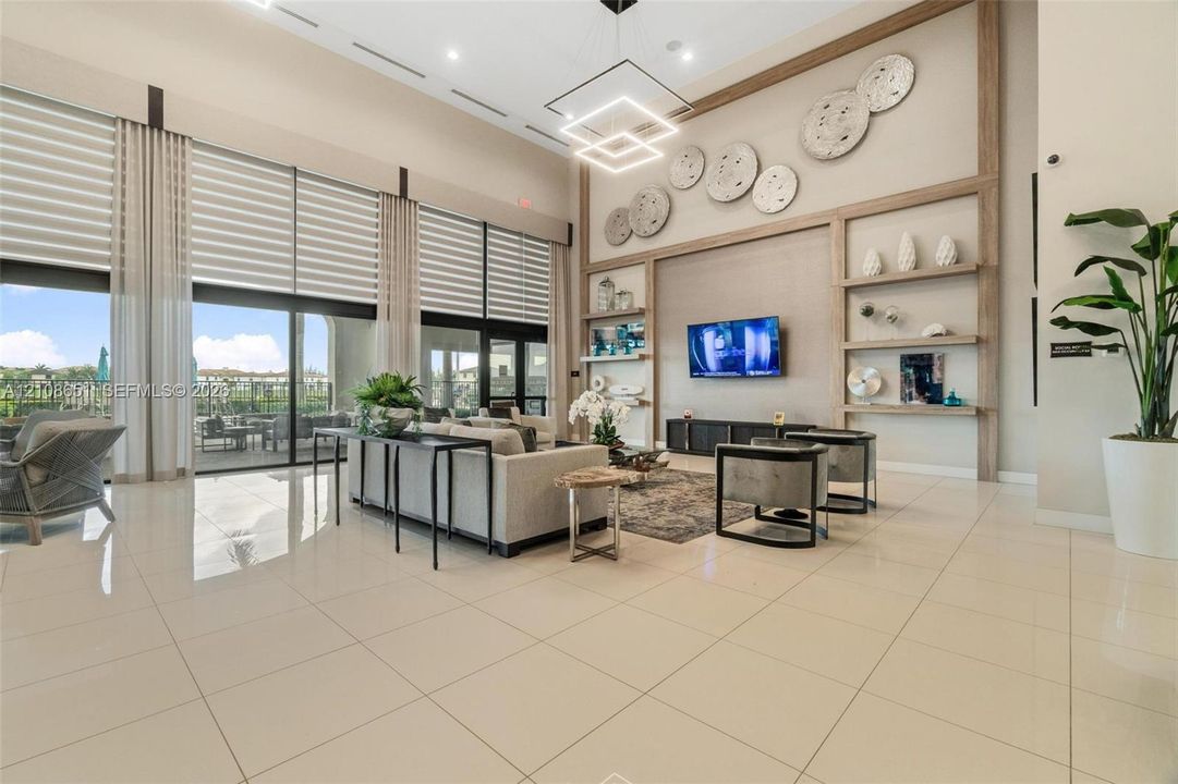 Great room with double-height ceilings, floor-to-ceiling glass wall, built-in wooden shelving, recessed lighting, and large-format tile flooring
