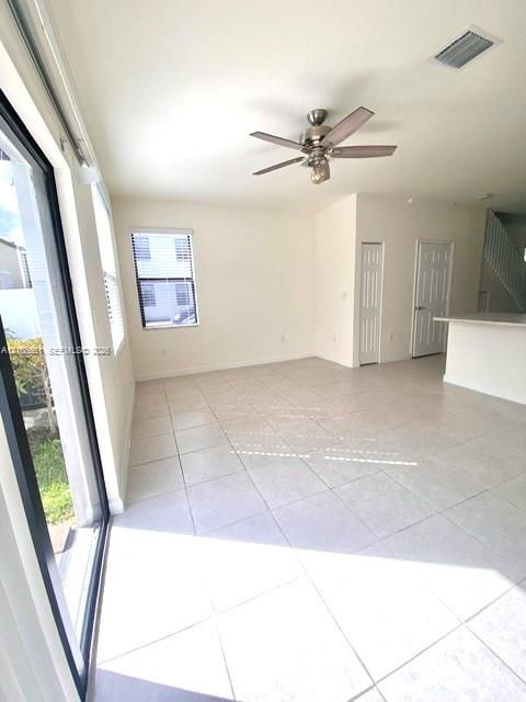 Open-concept interior featuring neutral tile flooring, recessed ceiling fan with integrated lighting, sliding glass door, and bi-fold closet doors