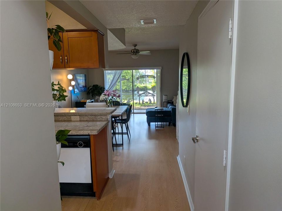 Wood-finish flooring, kitchen cabinetry, stone-finish countertops, ceiling fan, and sliding glass door
