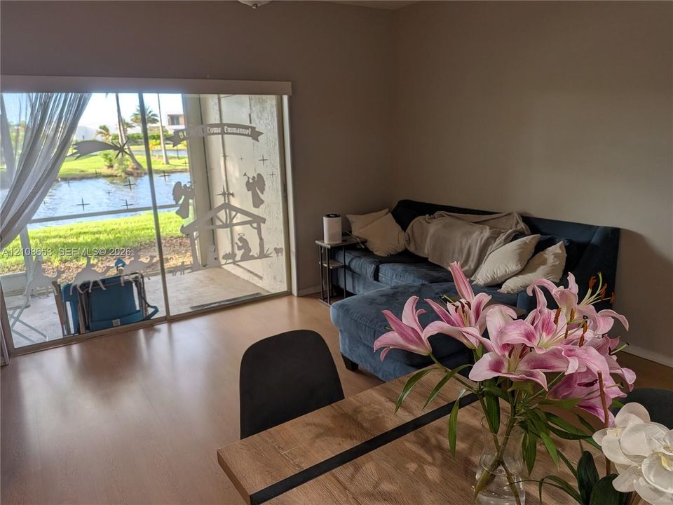 Large sliding glass doors opening to a concrete patio with water frontage and wood-finish flooring