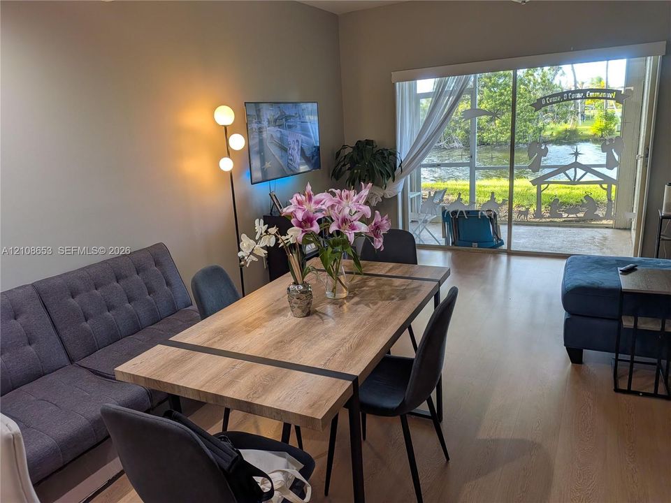 Living area featuring wood-finish flooring and large sliding glass doors leading to a screened-in patio with water frontage
