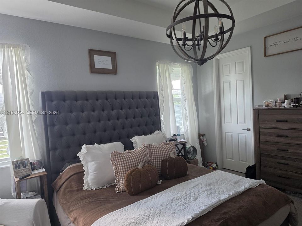 Tray ceiling featuring a contemporary spherical metal chandelier and a multi-panel interior door