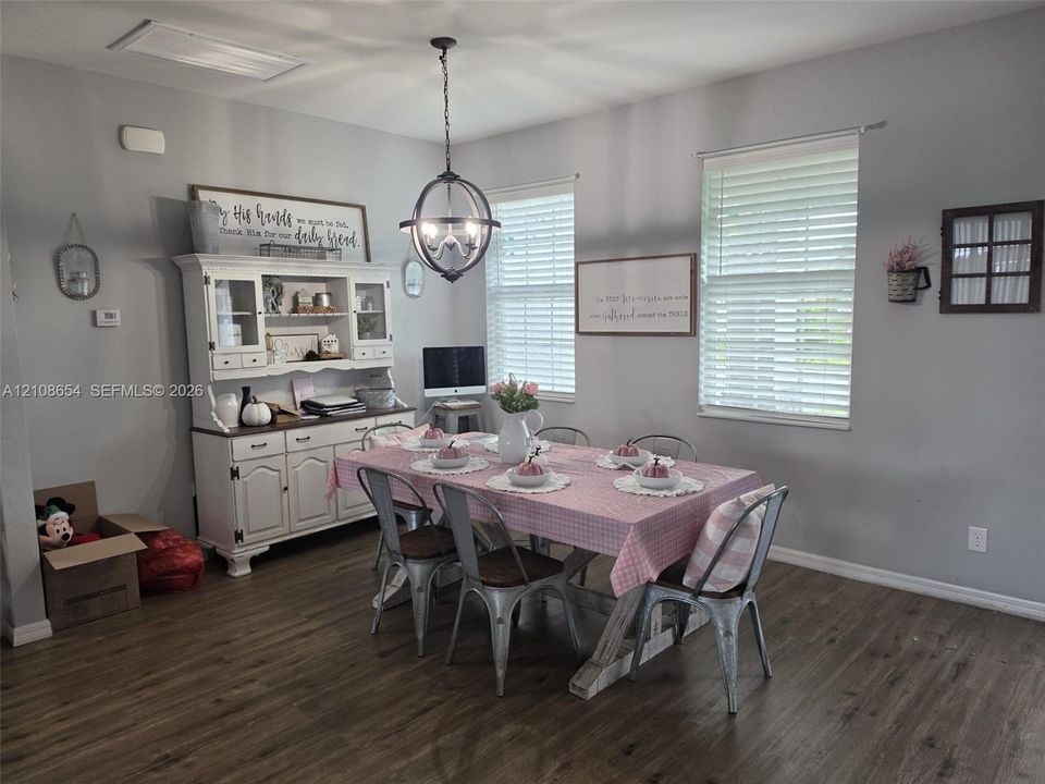 Dining area featuring wood-finish flooring, dual windows with fitted blinds, and a spherical metal chandelier