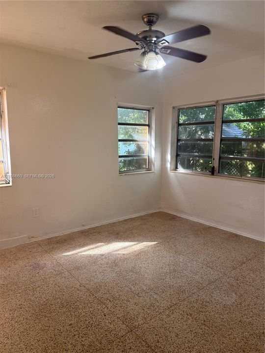 Interior space featuring light-toned tile flooring, multi-pane casement windows, and a ceiling-mounted fan with integrated light fixture