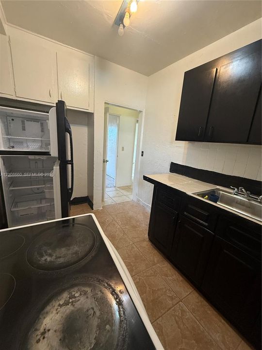Kitchen featuring contrast cabinetry, tiled countertop, stainless steel sink, and ceramic tile flooring