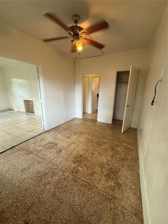 Room featuring textured flooring, ceiling fan with integrated lighting, and built-in closet storage
