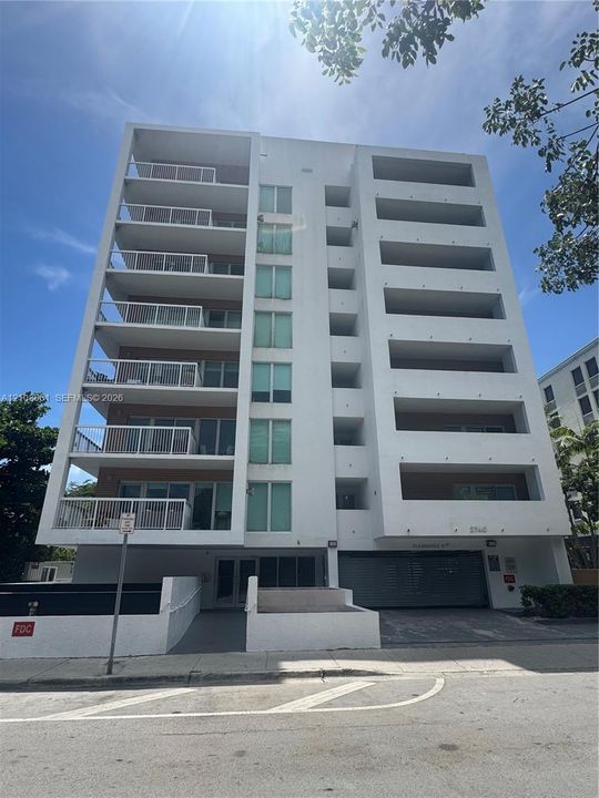 Multi-story high-rise exterior featuring white stucco facade, private recessed balconies, and integrated garage access