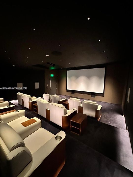 Dedicated media room featuring tiered flooring, large projection screen, and recessed fiber optic ceiling lighting