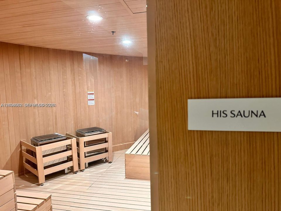 Sauna featuring natural wood-paneled walls and ceiling, tiered wood benches, and two integrated heating units with recessed lighting