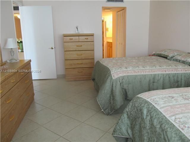 Room featuring neutral ceramic tile flooring, solid-core interior doors, and closet with louvered bi-fold doors